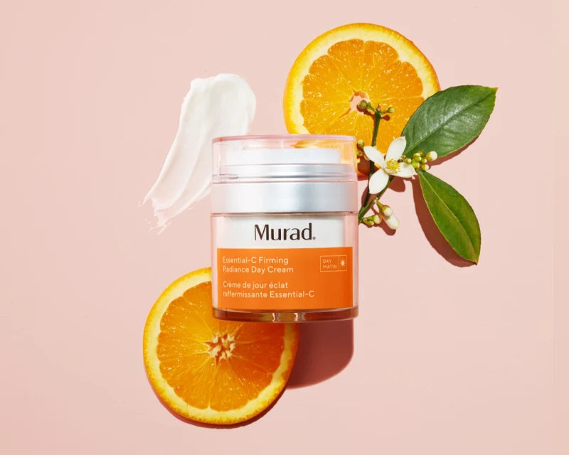 A jar of Essential-C Firming Radiance Day cream next to orange slices