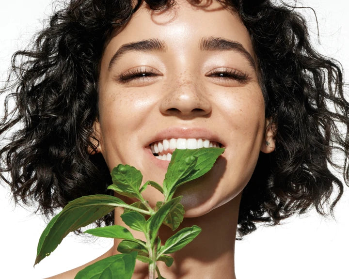a person with curly hair and a plant in her mouth