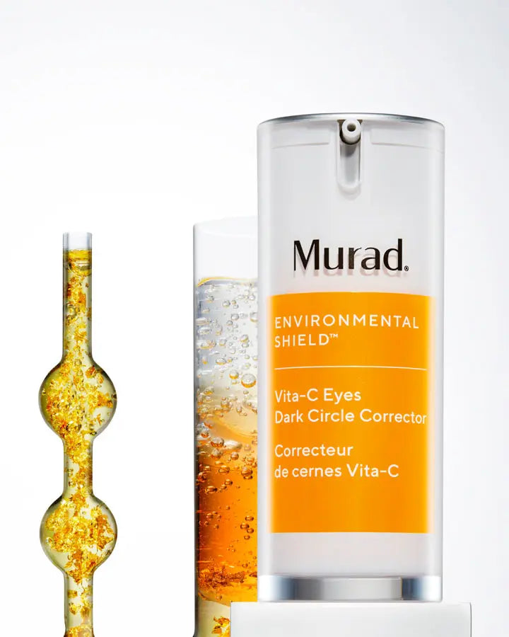 A container of Vita-C Eyes Dark Circle Corrector next to glass with organge liquid