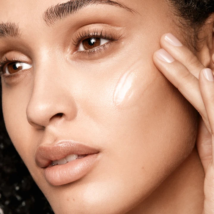 a person applying a clear serum to her face