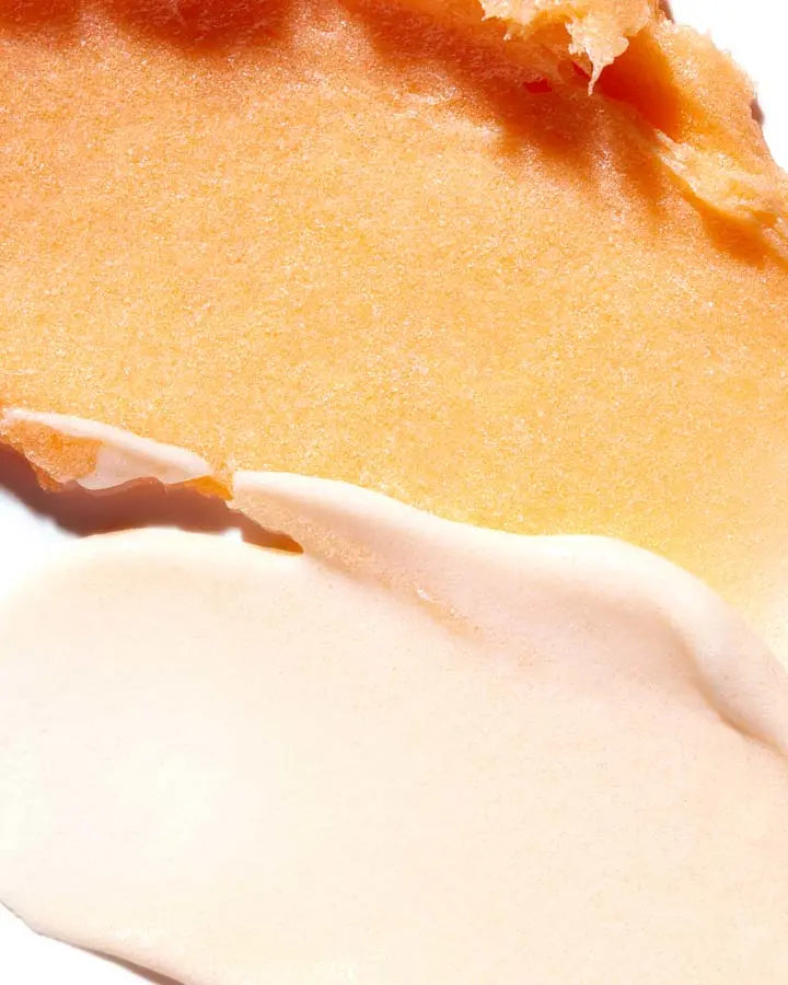 A close up of a white cream and orange exfoliator
