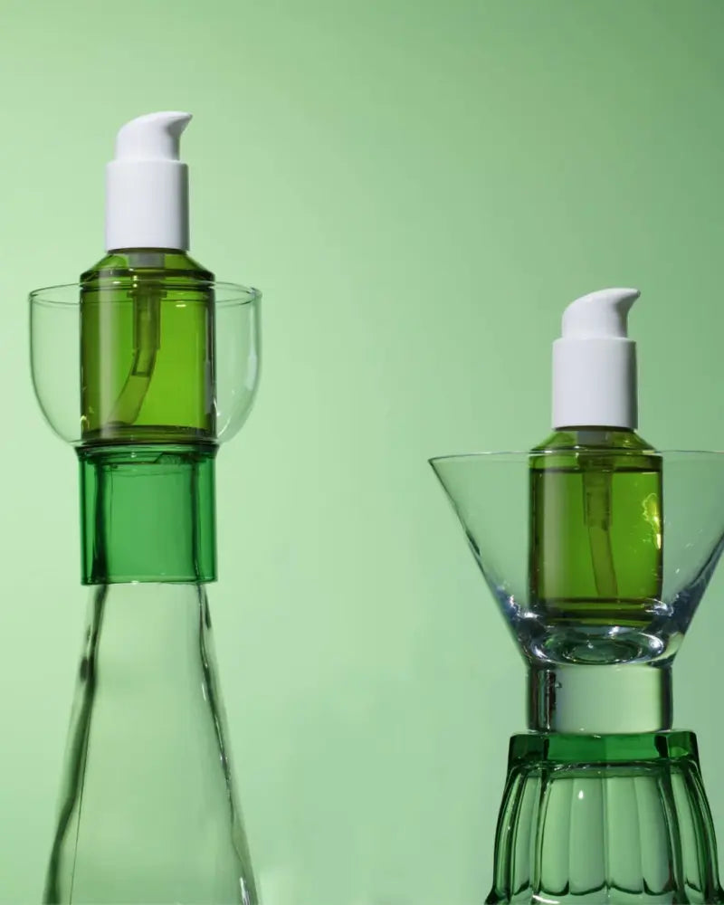 A couple of clear bottles with green liquid in them