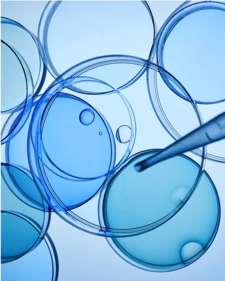 A close-up of a dropper dropping liquid into a group of blue circles