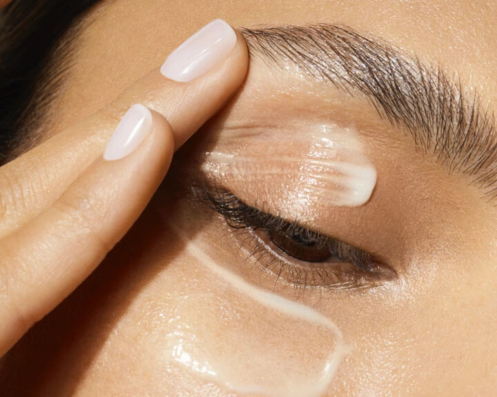 a close-up of a person applying cream on her eye