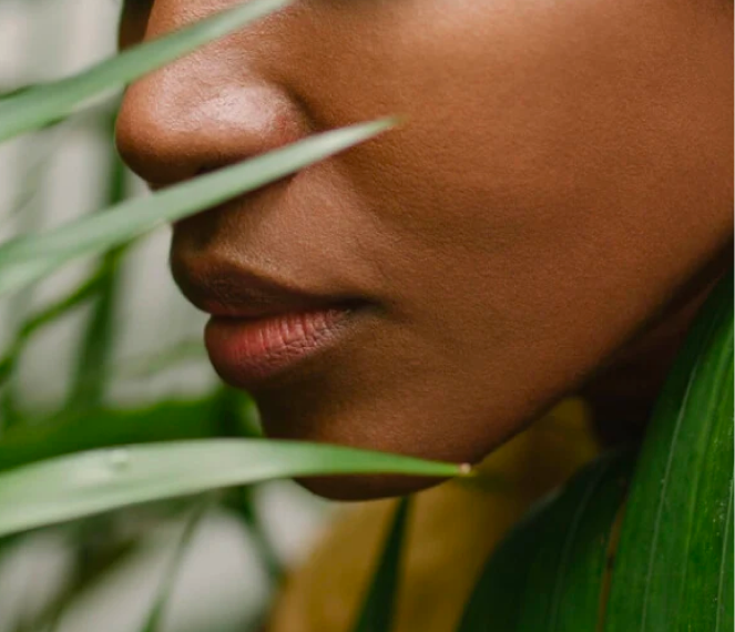 Side on close up of a cheek and mouth among plants and greenary