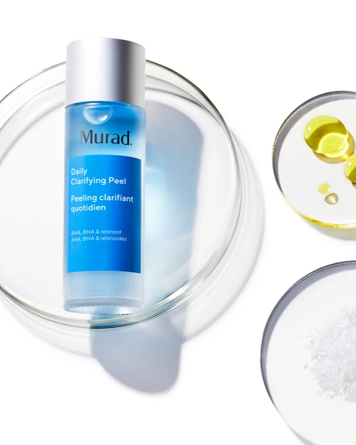 A clear dish with a bottle of Daily Clarifying Peel on top next to a round container with different ingredients